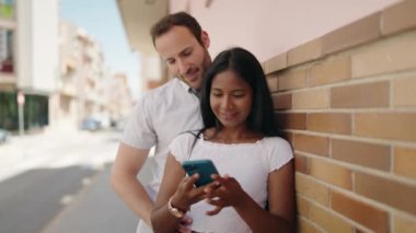 Man and woman interracial couple making selfie by smartphone at street