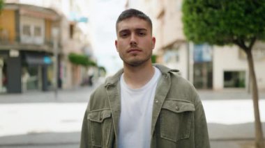 Young hispanic man doing angry gesture with fist at street