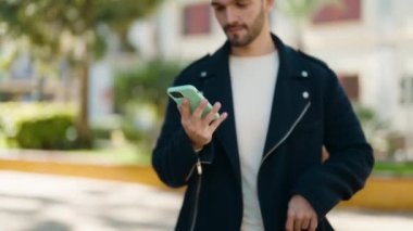 Parkta akıllı telefon kullanarak gülümseyen İspanyol genç adam.