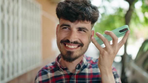 Молодой Латиноамериканец Улыбается Уверенно Слушая Аудиосообщение Смартфона Улице — стоковое видео