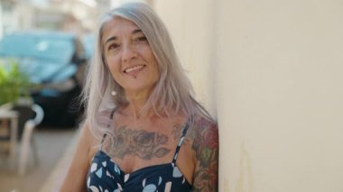Middle age grey-haired woman smiling confident looking to the side at street
