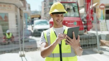 Young hispanic man architect using touchpad at park