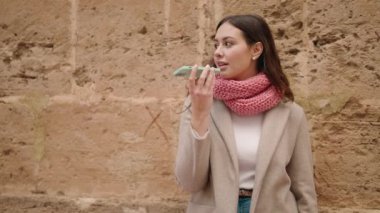 Gülümseyen genç bir kadın caddedeki akıllı telefondan konuşuyor.