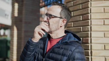 Middle age man standing with doubt expression at street