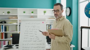 Orta yaşlı öğretmen sınıfta ders veriyor.