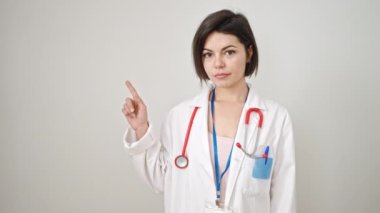 Kafkasyalı genç bir kadın doktor, izole edilmiş beyaz arka plan üzerinde parmak ucunda işaret ediyor.