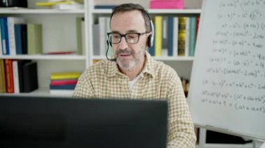Orta yaşlı bir öğrenci sınıfta video araması yaptığından emin gülümsüyor.