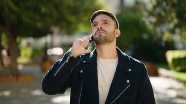 Genç İspanyol adam parkta akıllı telefondan konuşmaktan endişeleniyor.