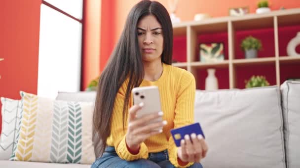 年轻美丽的惊慌失措的女人带着智能手机和信用卡在家里沙发上购物 — 图库视频影像