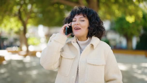 若いヒスパニック系の女性は 公園でスマートフォンで自信を持って話して笑顔 — ストック動画