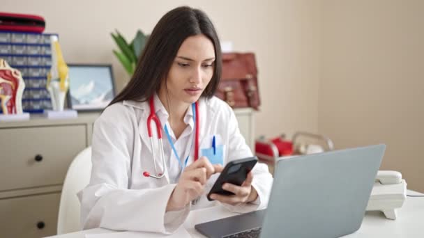 Joven Hermosa Mujer Hispana Médico Usando Portátil Teléfono Inteligente Que — Vídeos de Stock