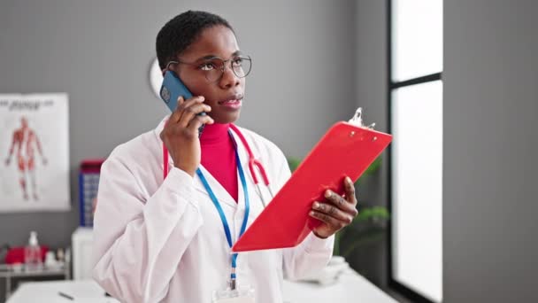 Αφροαμερικανή Γιατρός Μιλάει Στο Έγγραφο Ανάγνωσης Smartphone Στην Κλινική — Αρχείο Βίντεο