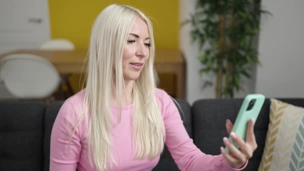 Mujer Rubia Joven Hacer Selfie Por Teléfono Inteligente Sentado Sofá — Vídeos de Stock