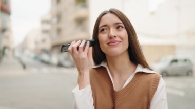 Young hispanic woman smiling confident listening audio message by the smartphone at street