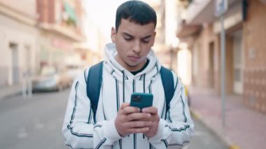 Young man student using smartphone standing at street