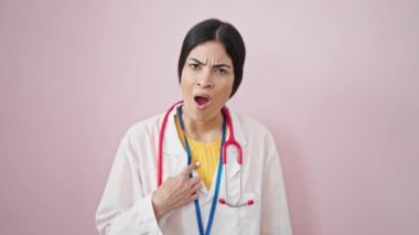 Genç, güzel İspanyol kadın doktor kendini göstererek, izole edilmiş pembe arka planda parmağıyla hayır diyor.