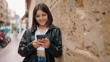 Sokakta akıllı telefon kullanan, kendine güvenen genç İspanyol kadın.