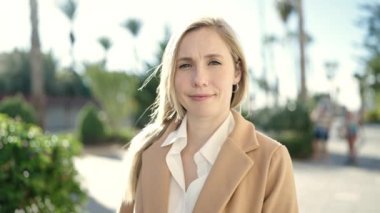 Parkta kendinden emin gülümseyen genç sarışın kadın.