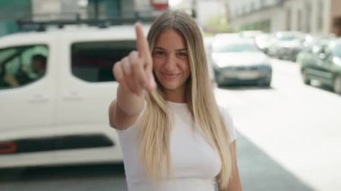 Genç, güzel İspanyol kadın gülümsüyor kendinden emin bir şekilde sokakta el kol geziyor.