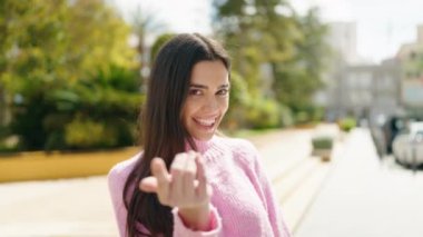Genç İspanyol kadın gülümsüyor. Kendine güveniyor. Parkta el kol hareketi yapıyor.