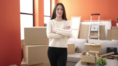 Young beautiful hispanic woman smiling confident standing with arms crossed gesture at new home