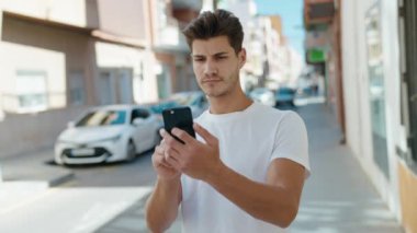 Genç İspanyol adam gülümsüyor. Parkta kendine güvenen bir video çağrısı var.