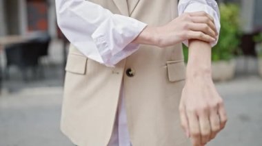 Genç, güzel, İspanyol bir kadın sokakta kaşınmak için kolunu kaşıyor.