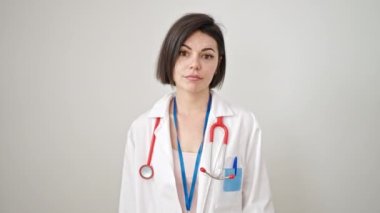Kafkasyalı genç kadın doktor şüpheli bir ifadeyle duruyor kolları izole beyaz arka planda.
