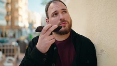 Sokakta akıllı telefondan konuşan genç ve cüsseli adam.