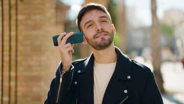 若いヒスパニック系の男笑顔自信を持ってリスニング音声メッセージによってスマートフォンでストリート — ストック動画