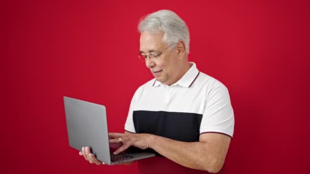 Orta Yaşlı Gri Saçlı Dizüstü Bilgisayarını Kullanan Kırmızı Arka Planı — Stok video