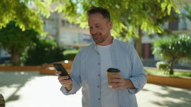 Mladý Kavkazský Muž Pomocí Smartphone Pití Kávy Parku — Stock video