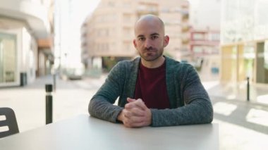 Kafe terasındaki genç kel adam.