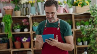 Çiçekçiye dokunarak gülümseyen orta yaşlı bir çiçekçi.