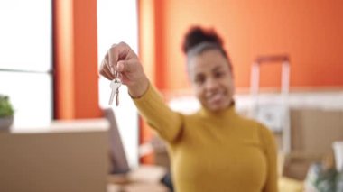 Genç Afrikalı Amerikalı kadın gülümsüyor. Yeni evinde kendine güveni tam.