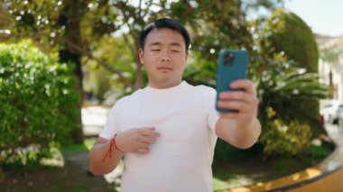 Young chinese man smiling confident having video call at park