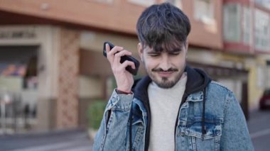Genç İspanyol adam kahve dükkanının terasında sesli mesaj dinliyor.