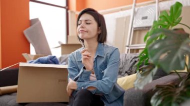 Kanepede oturan genç beyaz kadın yeni evinde yorgun olduğunu düşünüyor.