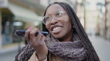 African woman sending voice message with phone at street