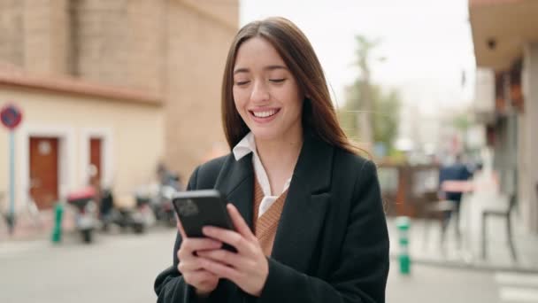 年轻的惊慌失措的女人在街上用智能手机充满自信地微笑 — 图库视频影像