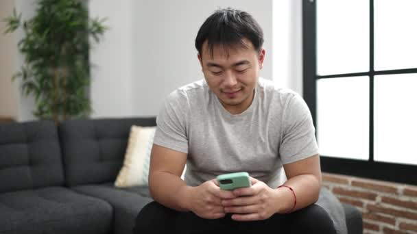 Jonge Chinese Man Met Behulp Van Smartphone Doet Gebaar Thuis — Stockvideo