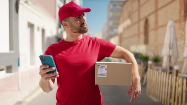 Young Hispanic Man Deliveryman Holding Package Using Smartphone Street — Vídeos de Stock
