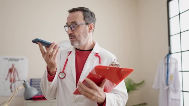 Medelålders Man Läkare Skicka Ljud Meddelande Läsning Medicinsk Rapport Kliniken — Stockvideo