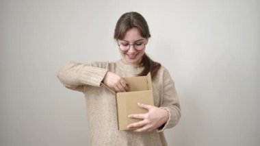 Genç sarışın kadın gülümsüyor, beyaz arka planda paketleri açıyor.