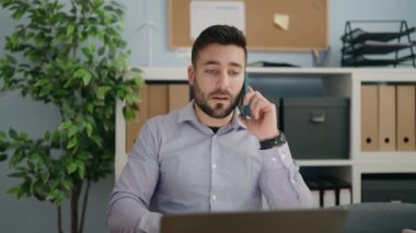 Genç İspanyol iş adamı ofiste çalışan akıllı telefondan konuşuyor.