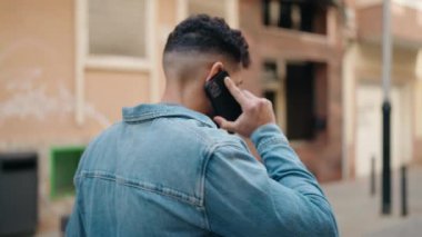 Sokakta yürürken akıllı telefondan konuşan genç bir Arap.