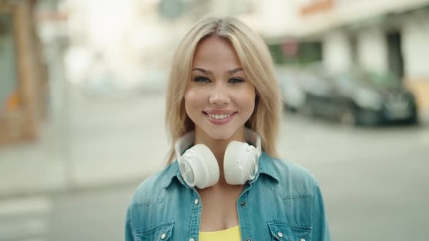 Mujer Rubia Joven Sonriendo Confiada Usando Auriculares Calle — Vídeo de stock