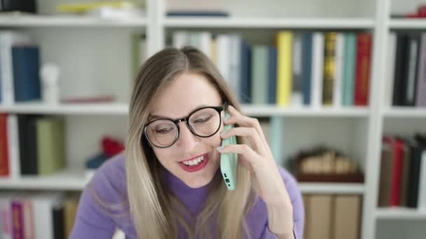 Молодая Блондинка Студентка Помощью Компьютера Разговаривает Смартфоне Библиотечном Университете — стоковое видео