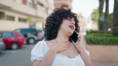 Orta Doğulu genç bir kadın gülümsüyor. Akıllı telefondan konuşuyor.