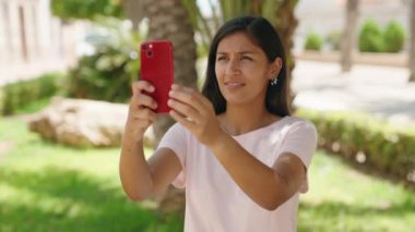 Young beautiful hispanic woman smiling confident make photo by smartphone at park